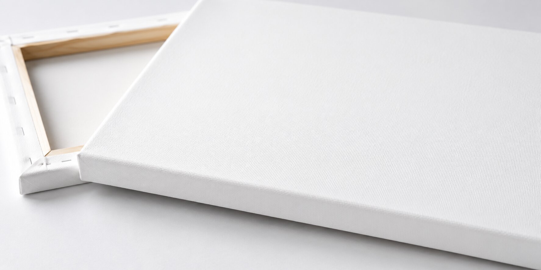 Białe płótno canvas w zbliżeniu z widoczną strukturą materiału i drewnianą ramą